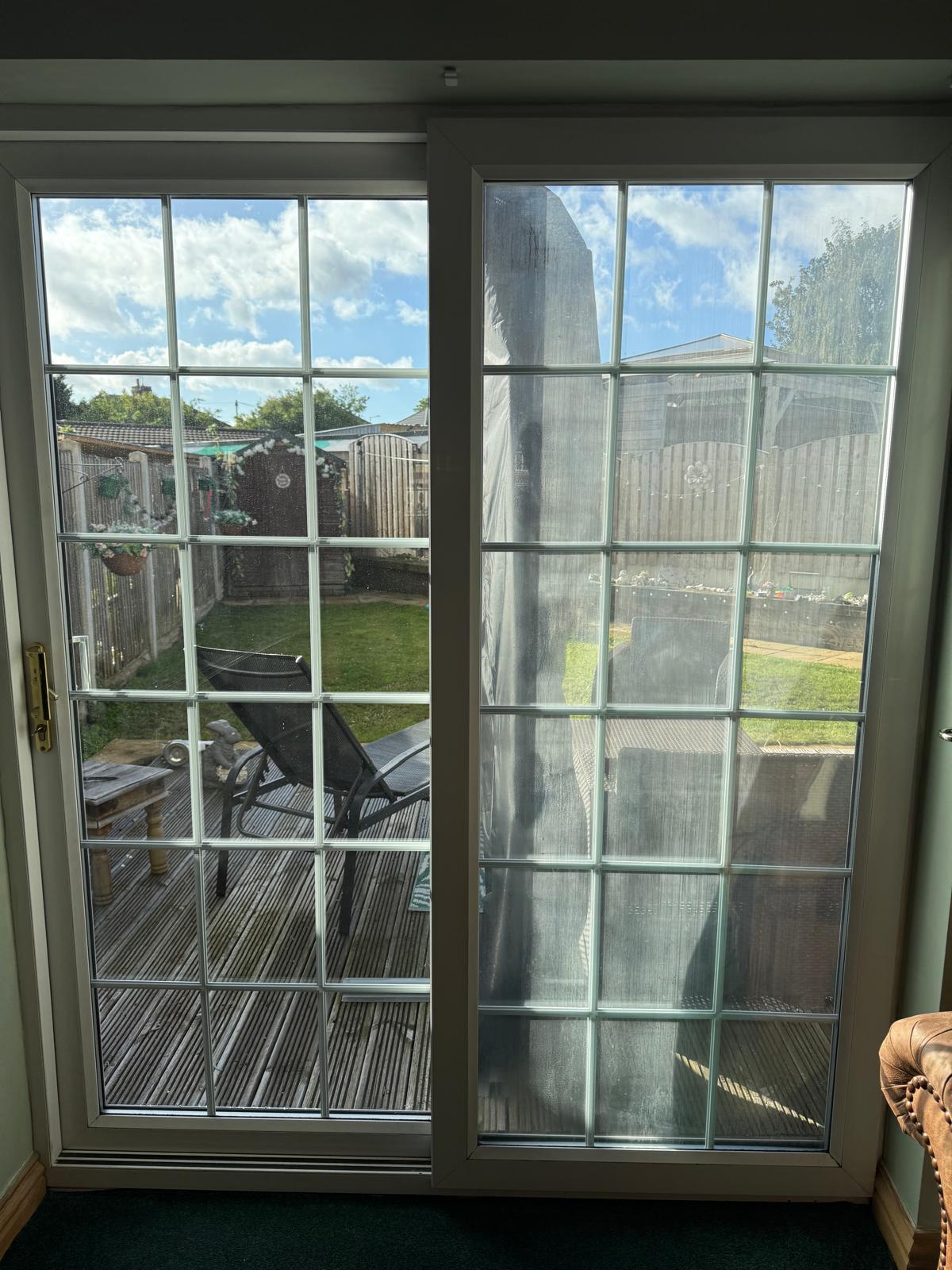 Before: white Georgian bar sliding patio door seen from inside, the right hand pane misted and streaked where the sealed unit has failed